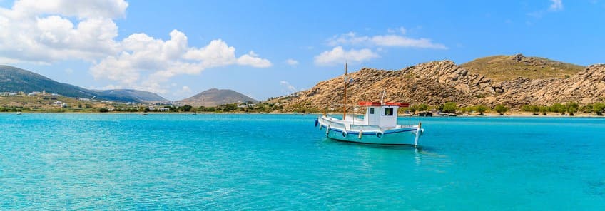 Красивое голубое море по путевкам в Грецию, лазурное море, белый катер и зеленые скалы